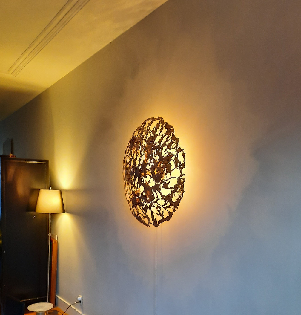 Sculpturale bronzen wandlamp die warm licht op de muur werpt